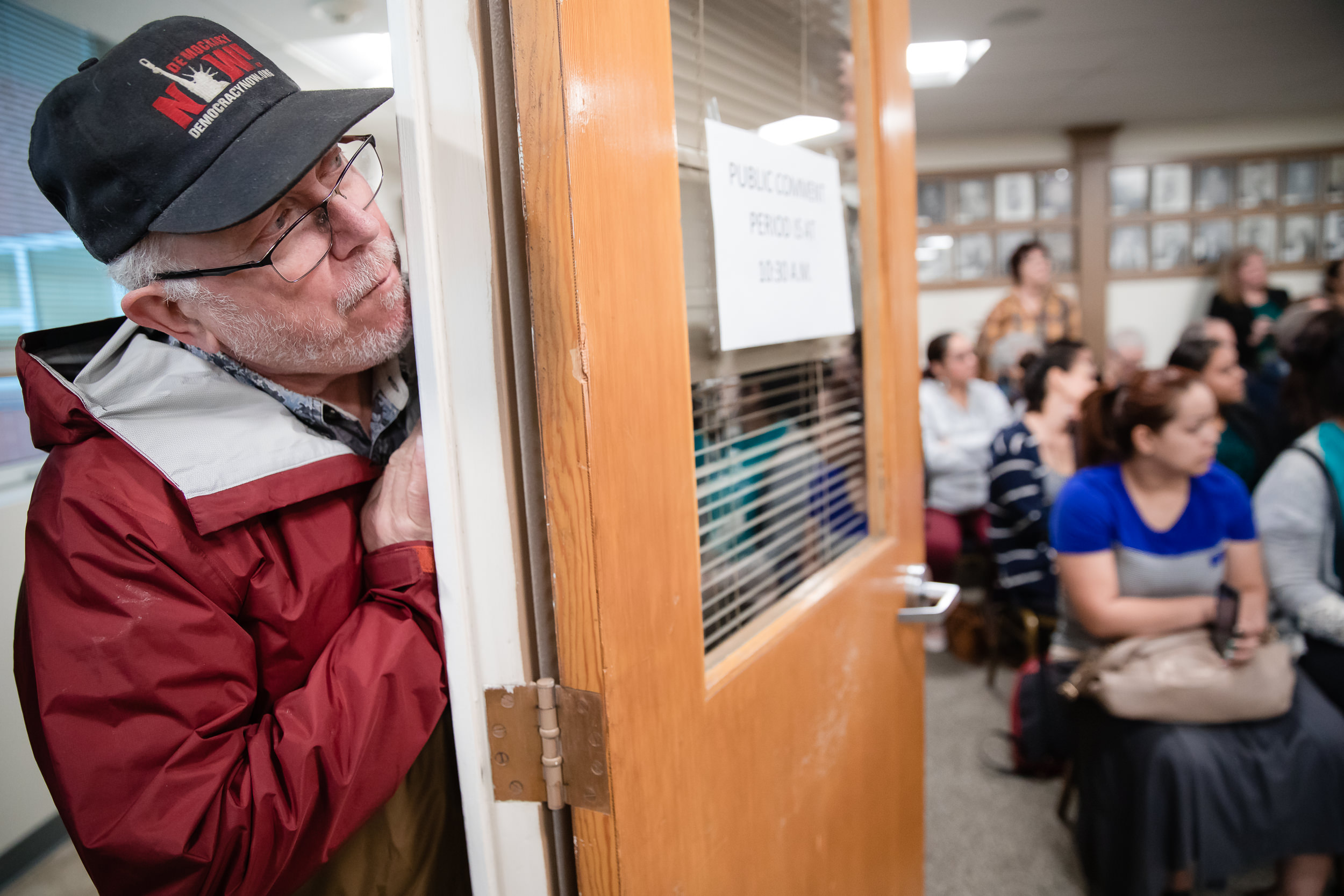 Steve Parker, with the Spokane Immigrants Rights Coalition, peeks around a doorway to listen to comments