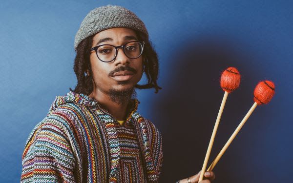 A young man in glasses with vibraphone mallets