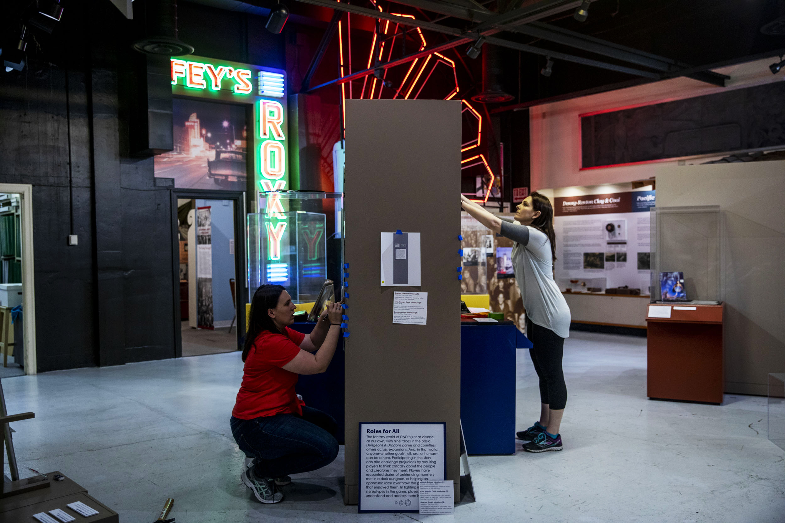 Renton History Museum curator Sarah Samson, right, and exhibit curator Allison Moore work on installing the museum's upcoming exhibit titled 'Hero's Feast: Finding Community through Dungeons and Dragons' on April 30, 2019. The exhibit will open on May 7. (Photo by Dorothy Edwards/Crosscut)