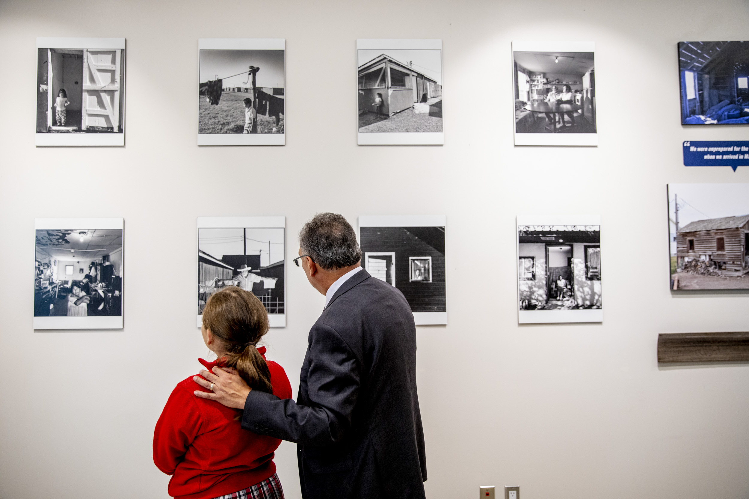 a man shows a wall of historic photos to a young girl