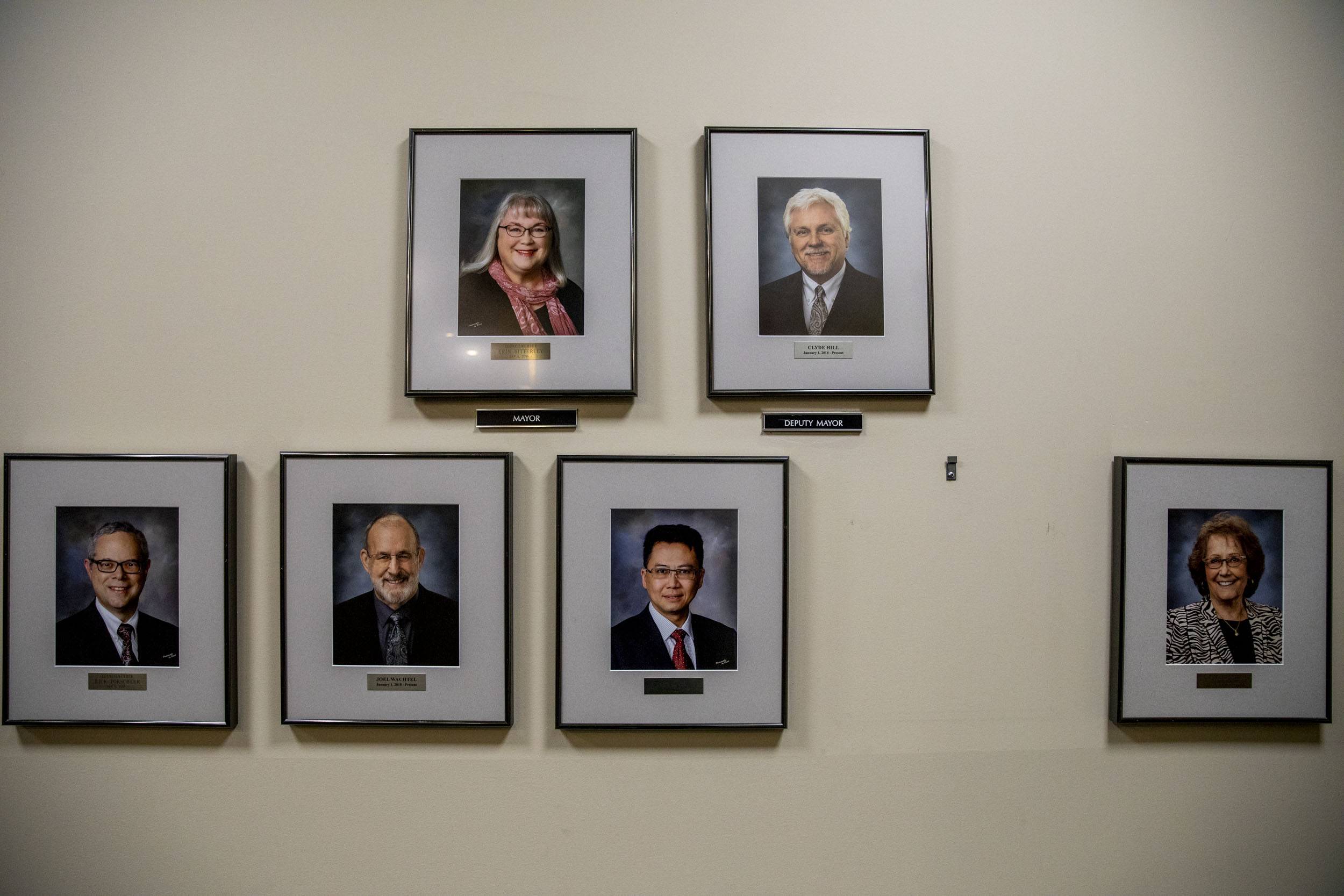 Photos of each SeaTac councilmember on a wall and a blank space where the new councilmember's headshot will be