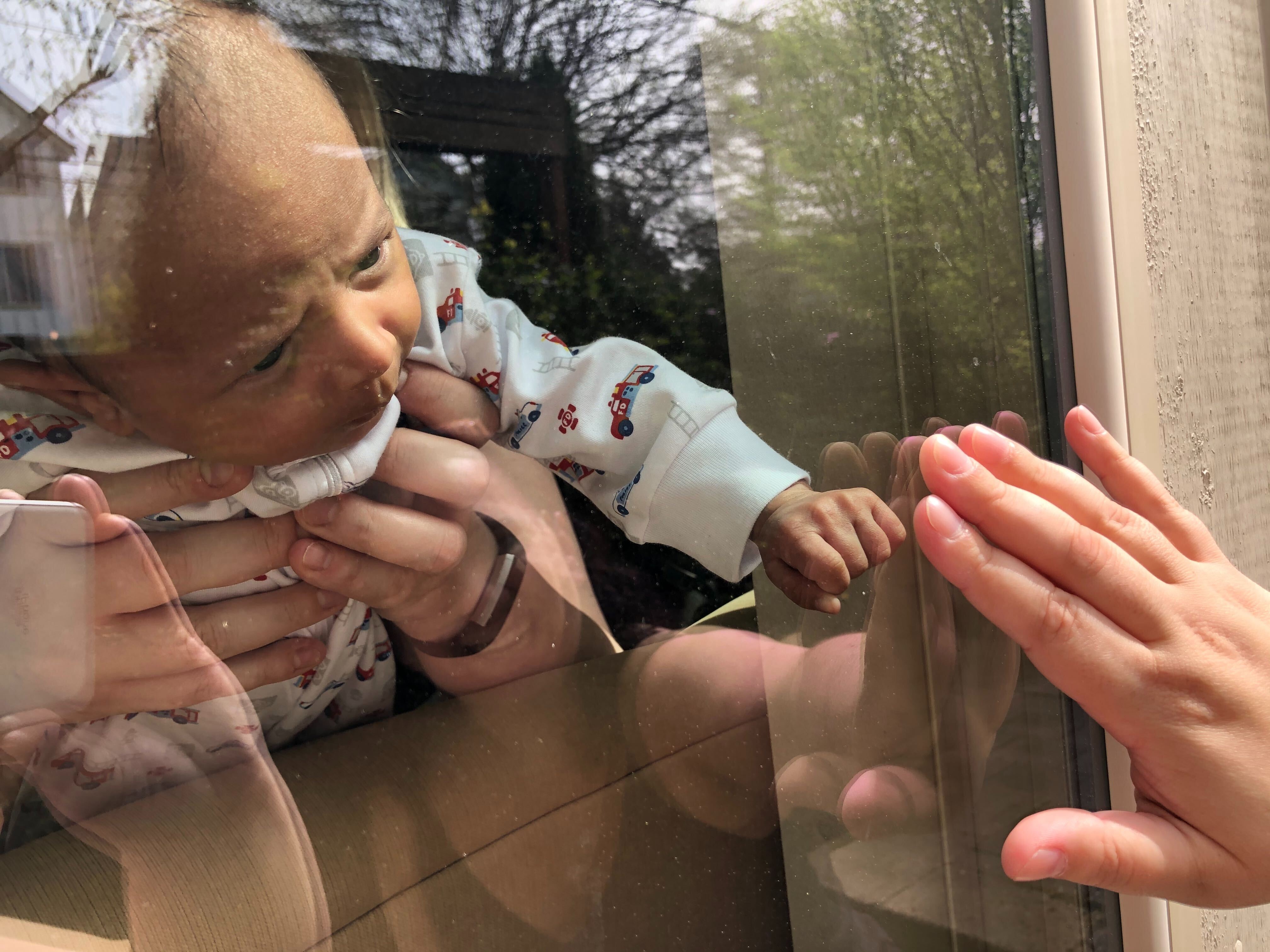 little baby touches hand through glass