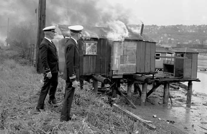 Naval officers watching Hooverville shack burn