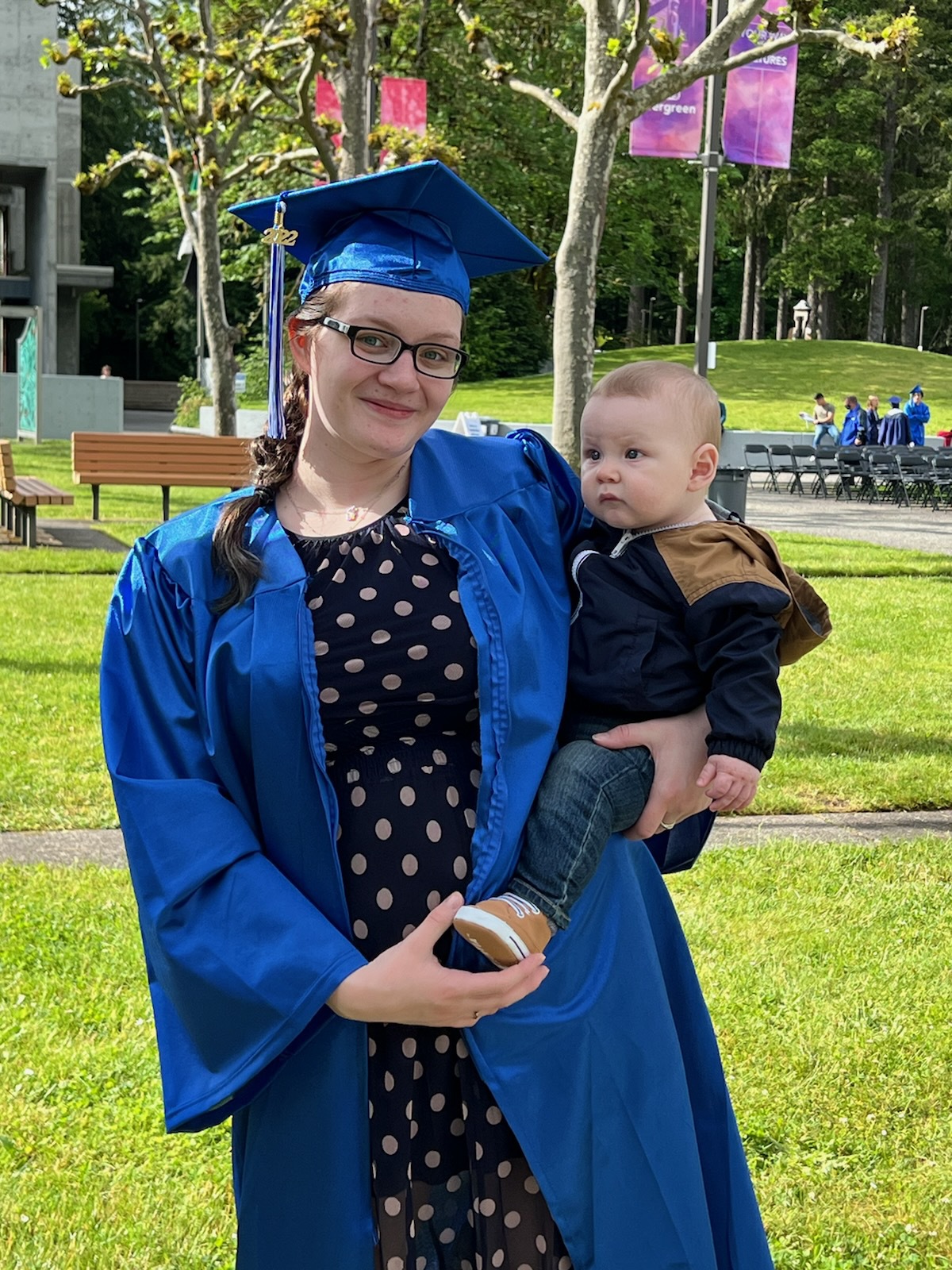 Ivy Group holds her baby while wearing a graduation gown