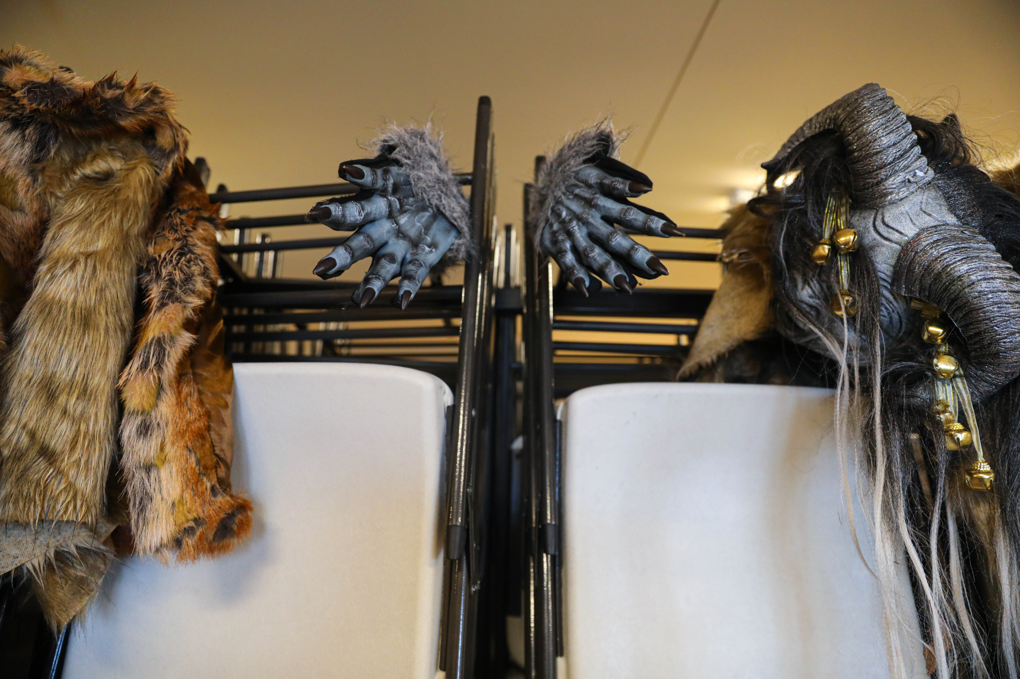 Krampus gloves and other costume parts hang from a rack of chairs