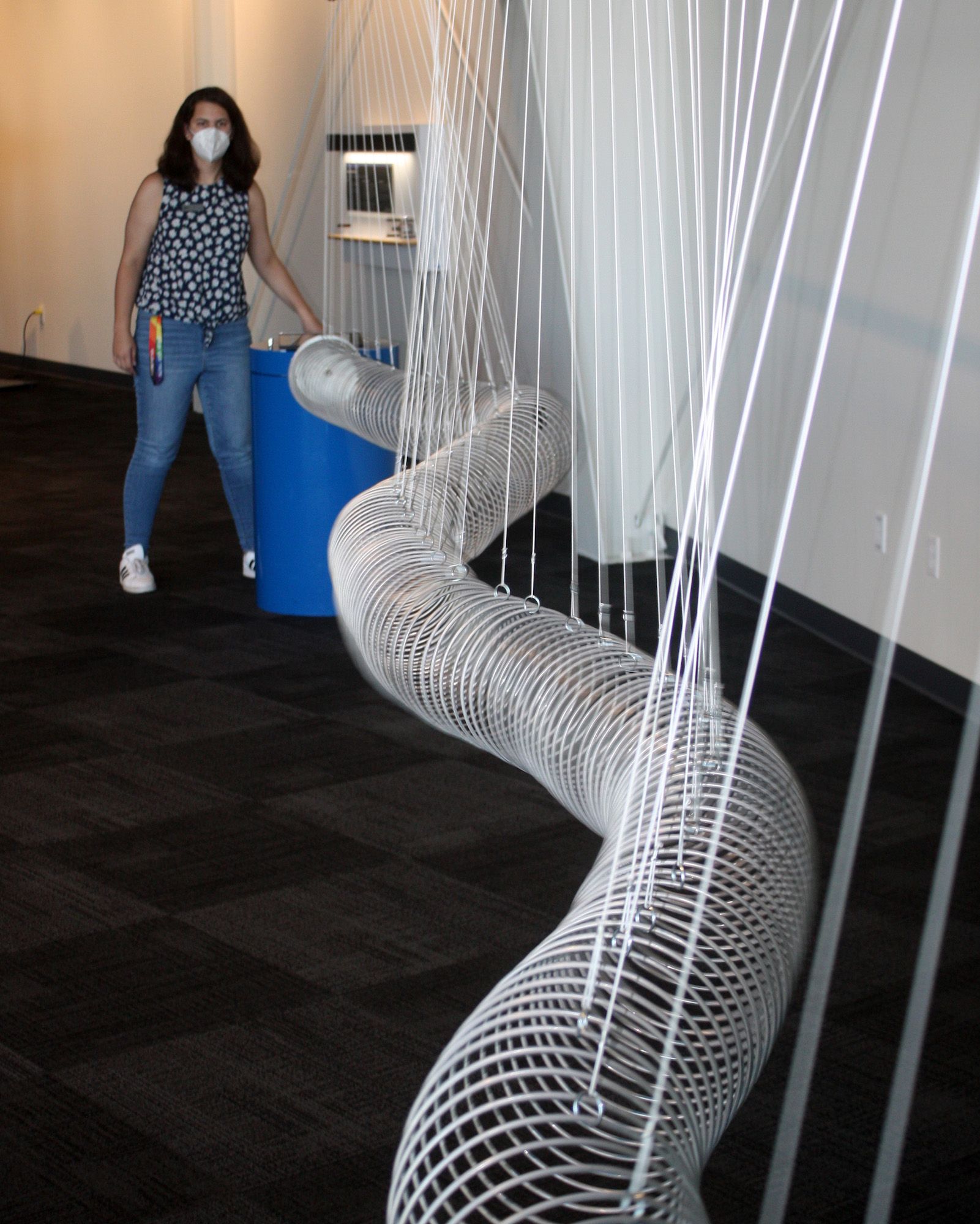 A person stands at the end of a long, suspended Slinky