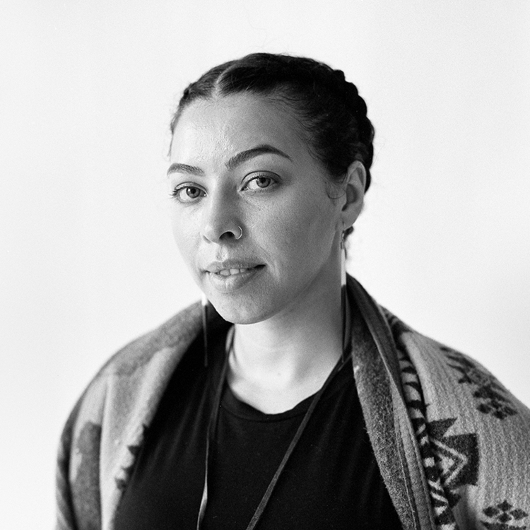 a black and white photo of a woman wearing braids and a blanket