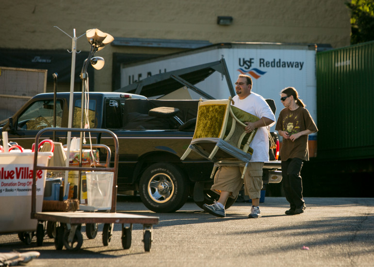 A man carried a chair to a pile of household items near a Value Village store