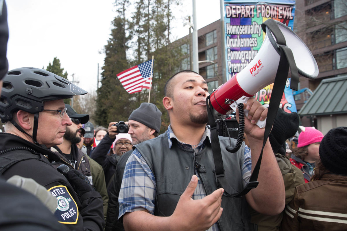 Tusitala “Tiny” Toese, of Vancouver, Washington shouts through a megaphone after joining the Patriot Prayer counter protesters during the Seattle Women’s March 2.0 in Seattle, Jan. 20, 2018.