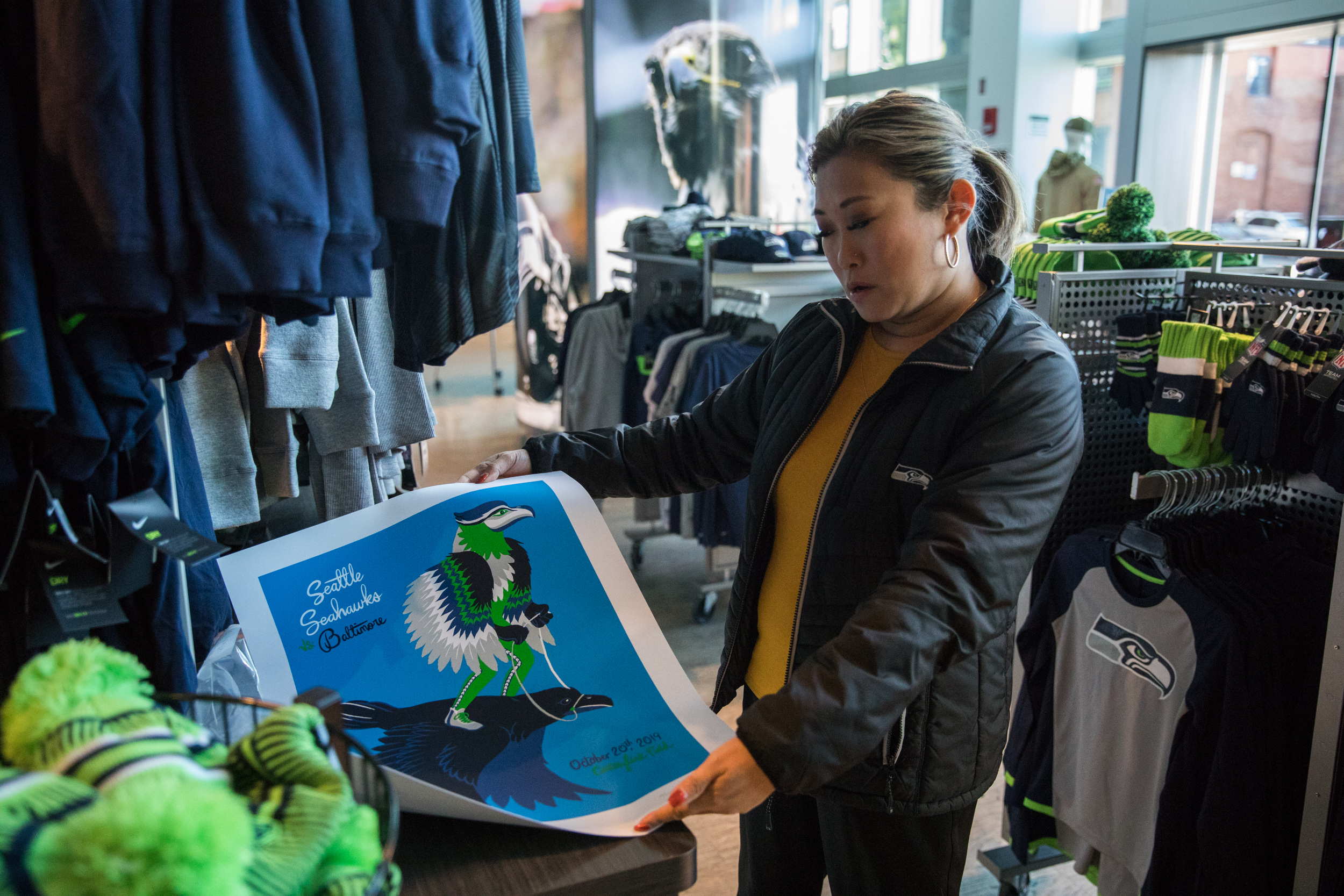 Woman unfurls a poster in the Seahawks pro shop