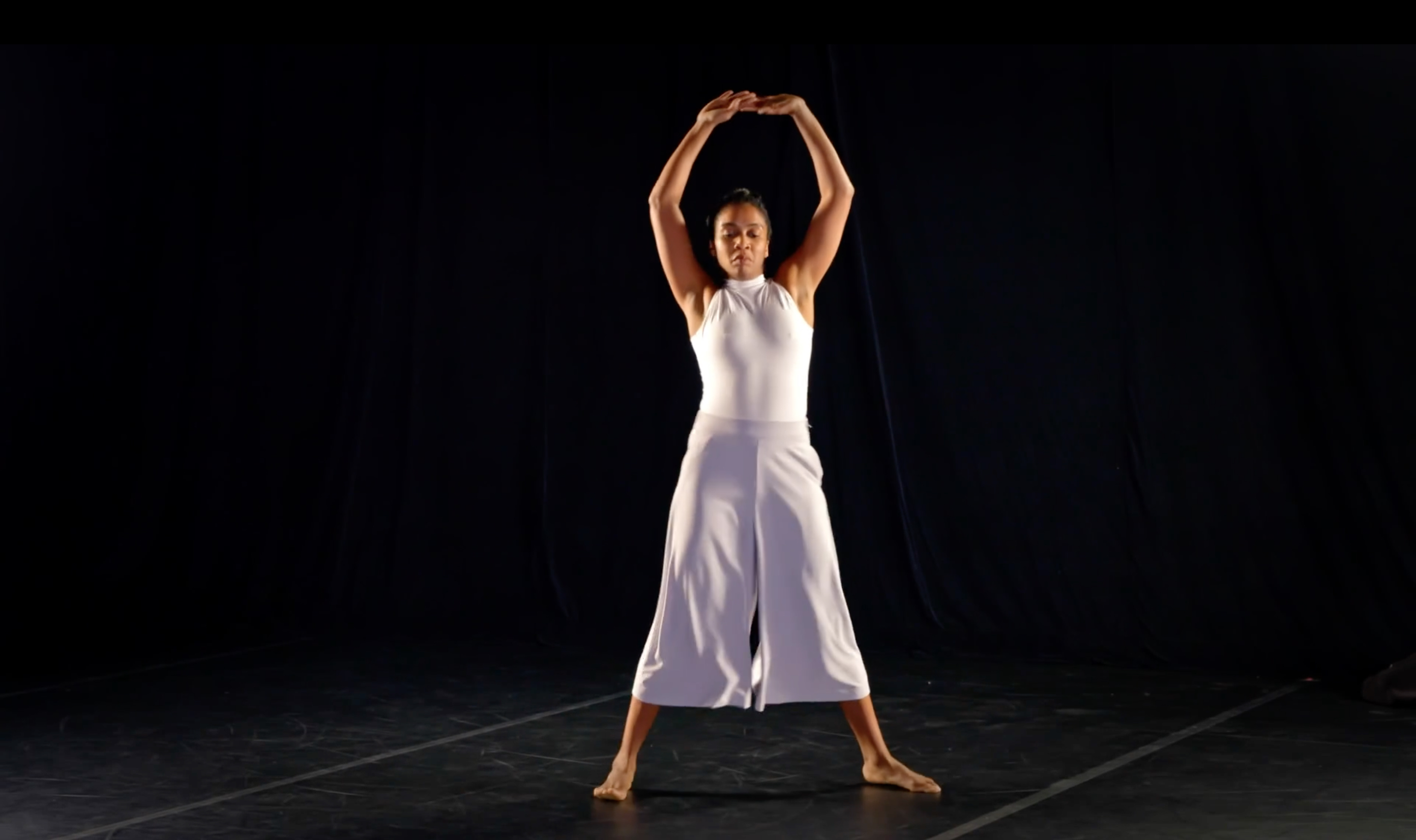 a woman dances in white top and pants