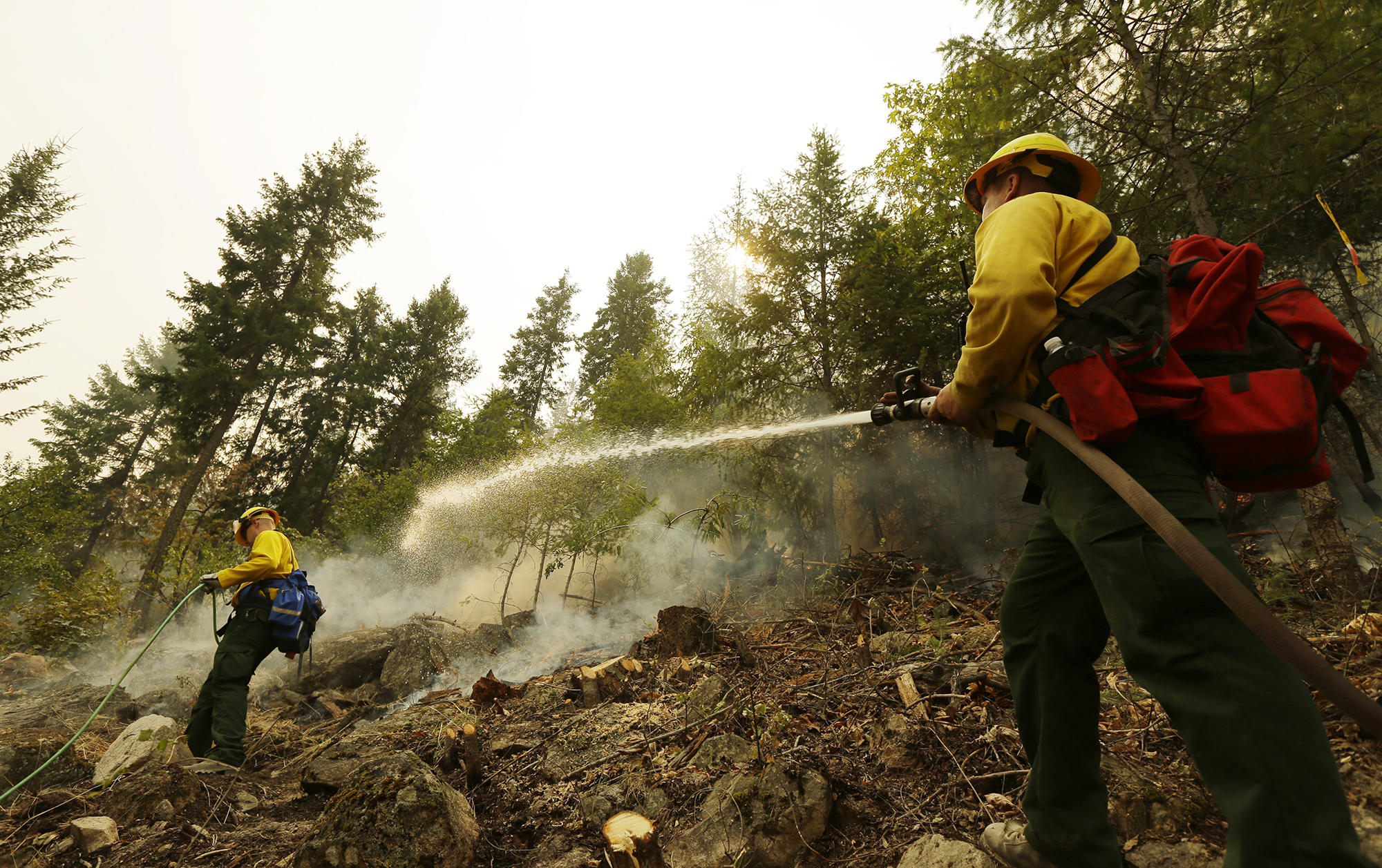 Colby Lyon, of the Central Region Strike Force Team II, sprays a hillside with water as part of the response to a fire near Chelan, Wash. on Aug. 18, 2015.
