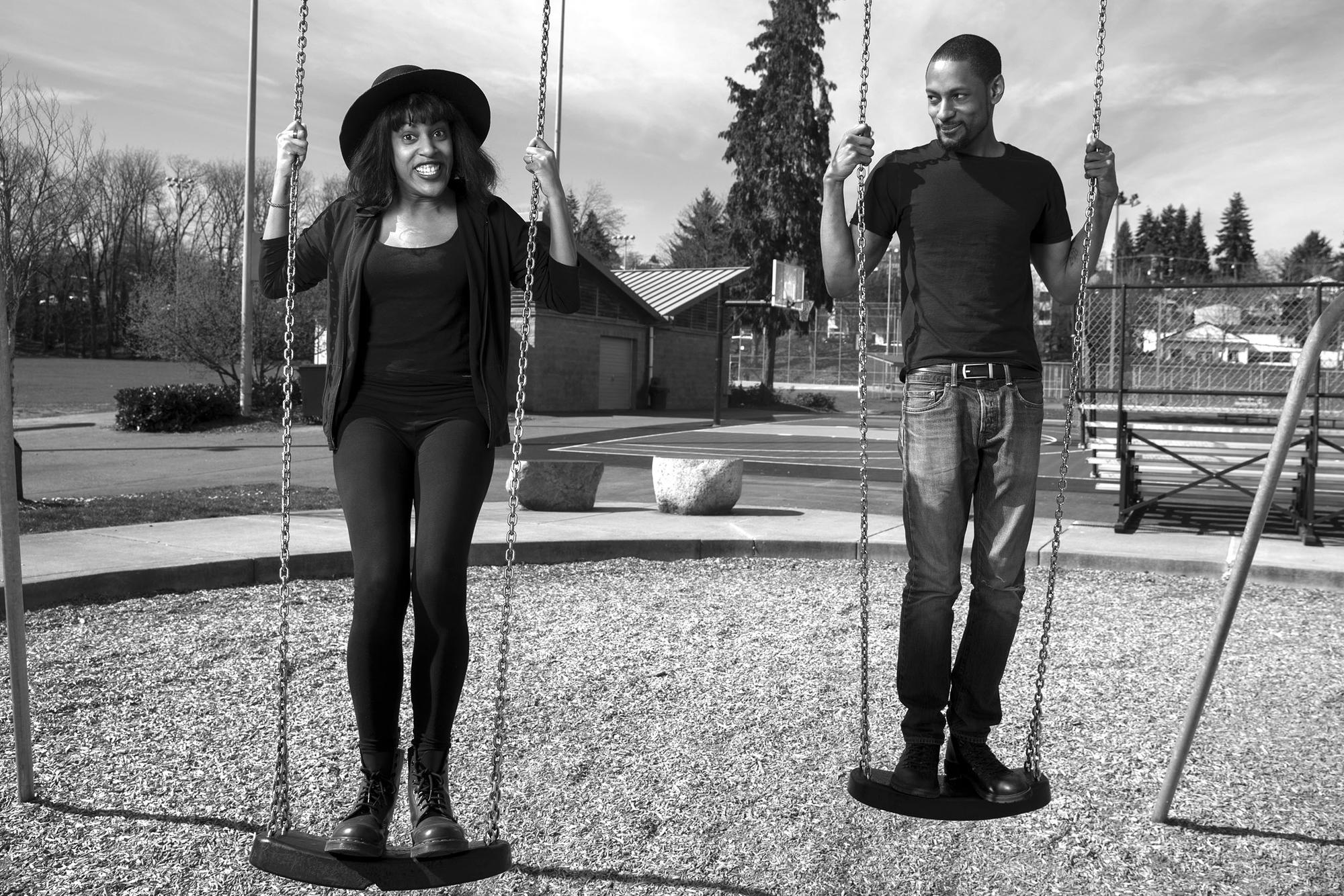 black and white photo of two people on swings