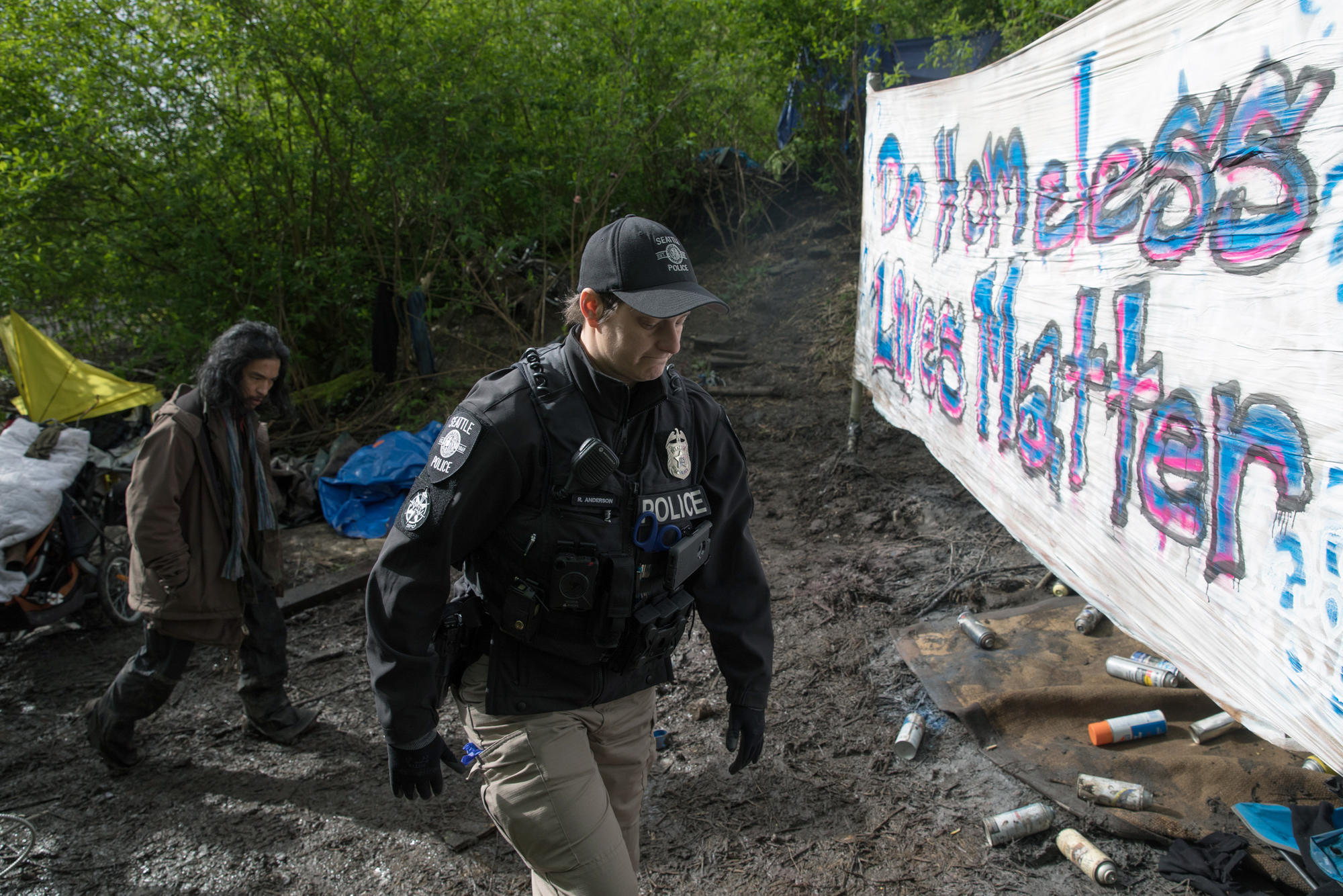 A Seattle Police Department officer is seen walking into the encampment with a tenant, during a sweep of Ravenna Woods homeless encampment near Seattle's University Village neighborhood, Tuesday, April 17.