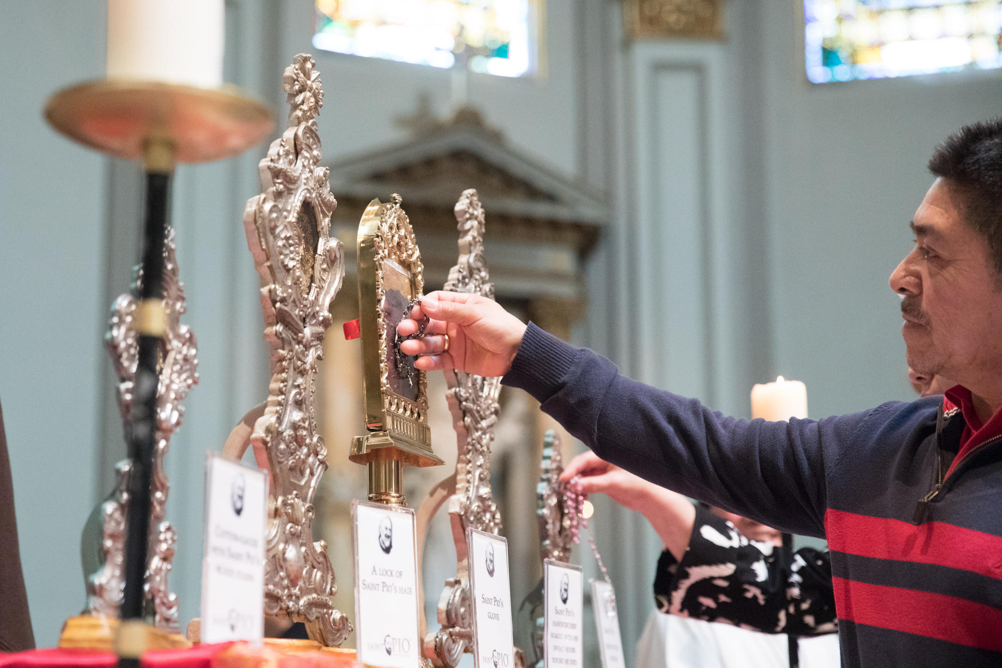 A church visitor touches his rosary beads to Padre Pio's relics during a public veneration at St. James Cathedral in Seattle. 