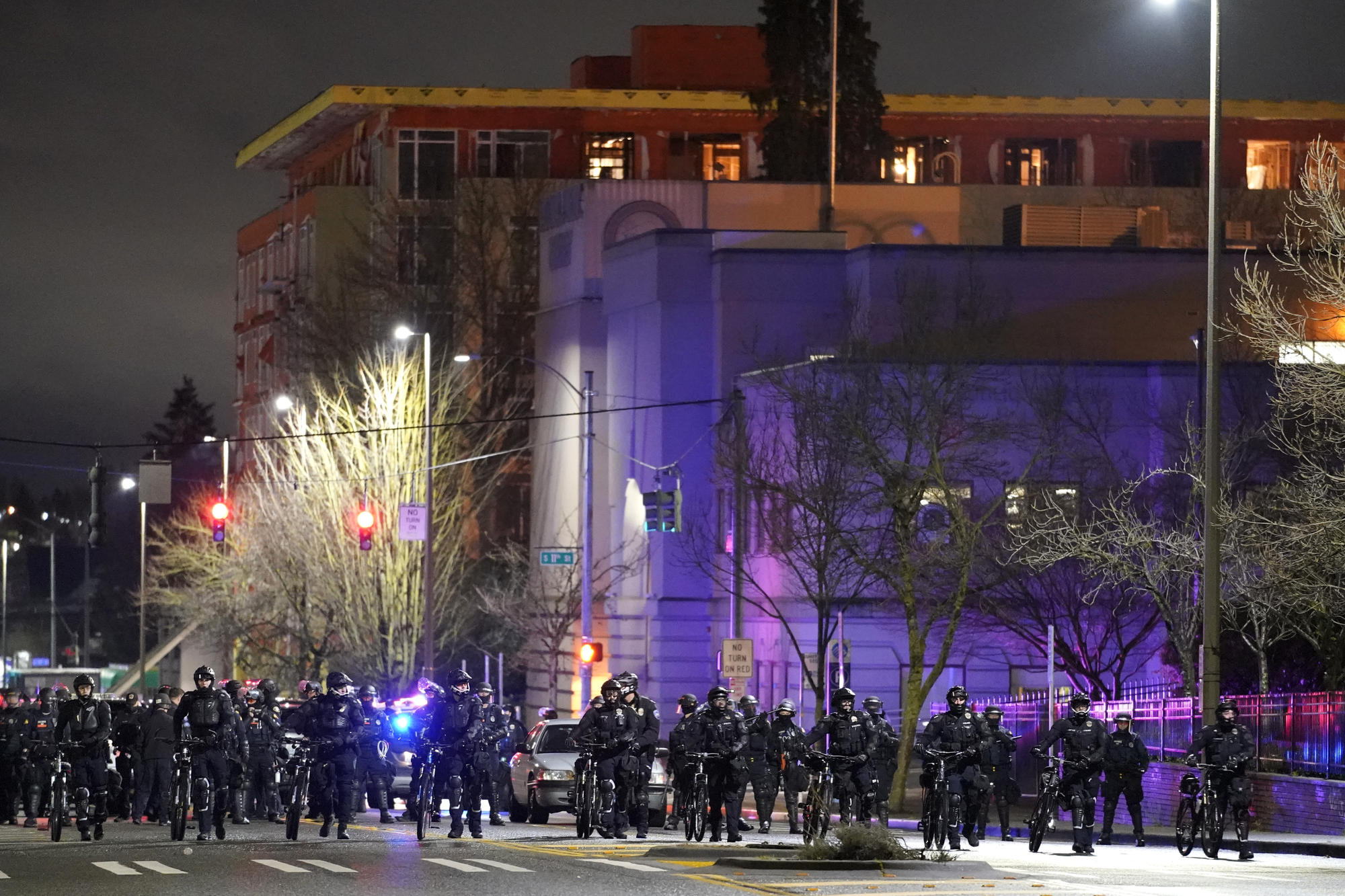 A line of police officers on a street with a building behind them