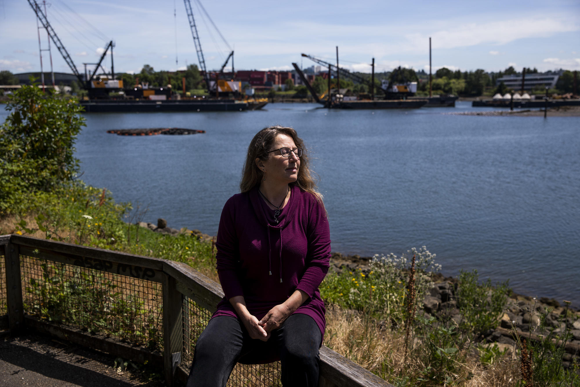 A woman sits on a railing along the Duwamish River