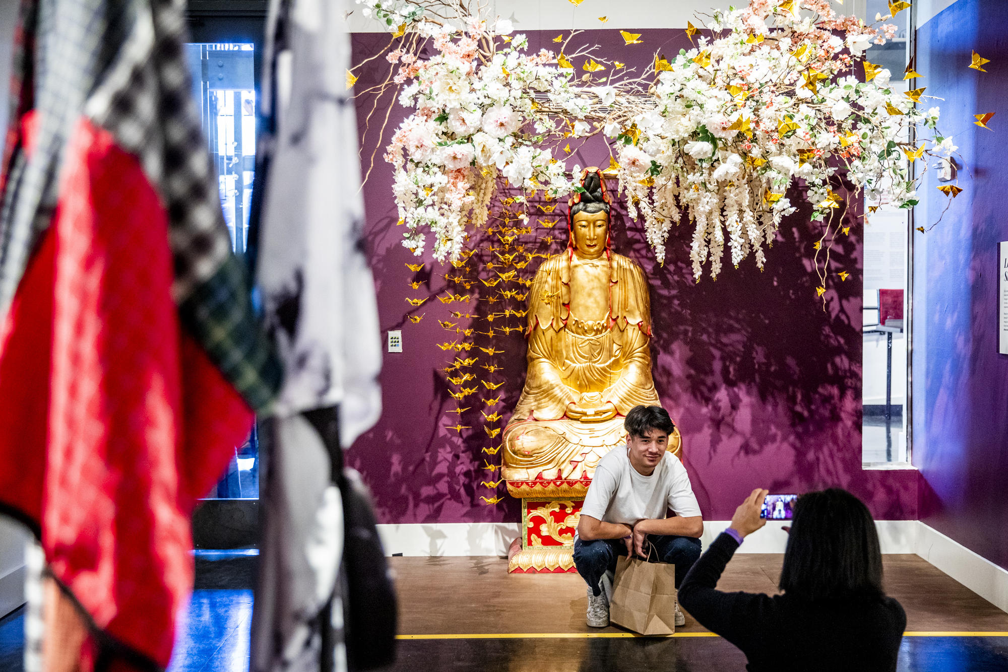 Keats kneeling in front a Buddha statue