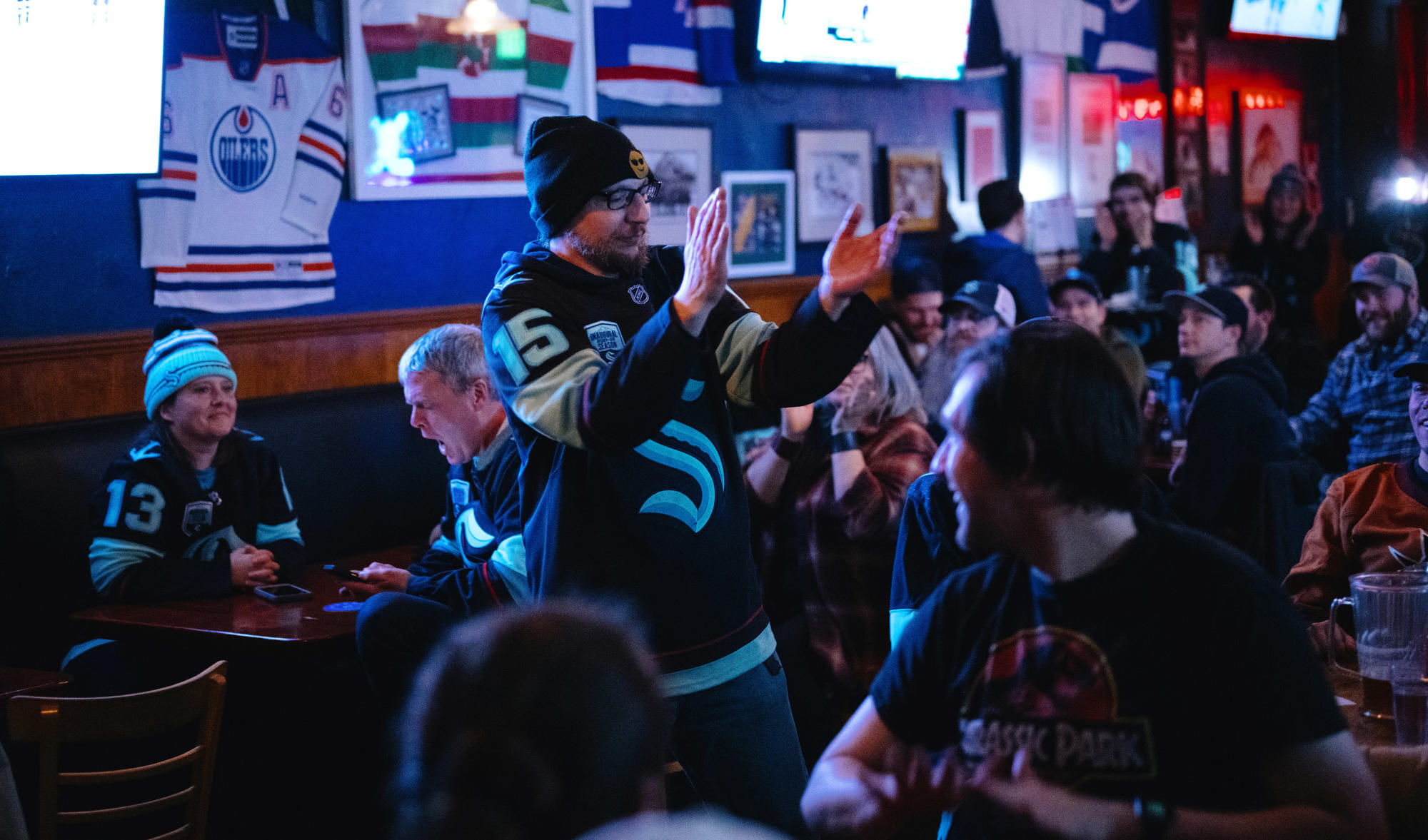 A fan stands in a Kraken jersey in a bar