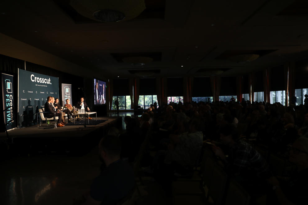 A panel of experts discuss climate change before a large audience.