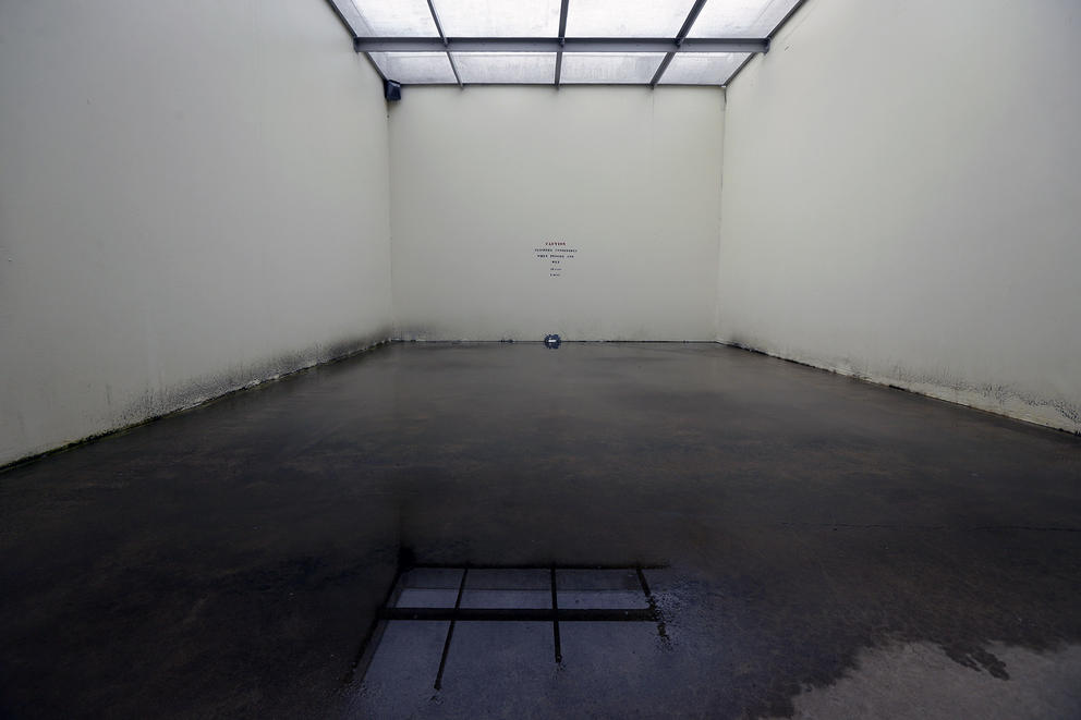 An empty room with a puddle on the floor at a Washington corrections facility.