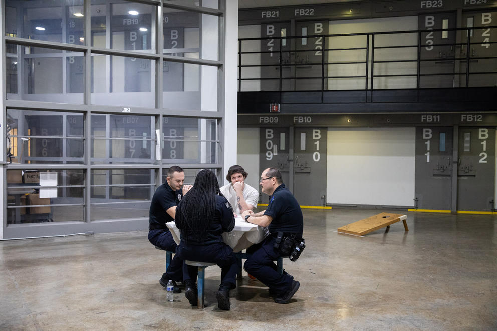 Four people sitting at a table in a concrete room