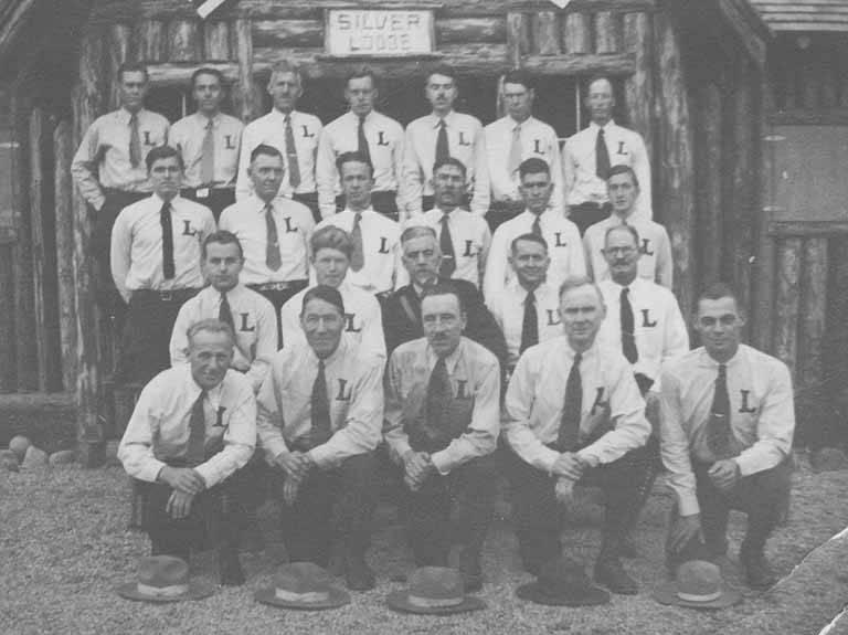 A group of men wearing white shirts and ties pose in three rows