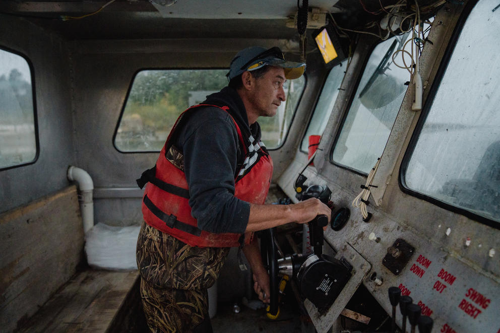 A man stands behind the wheel of a fishing boat