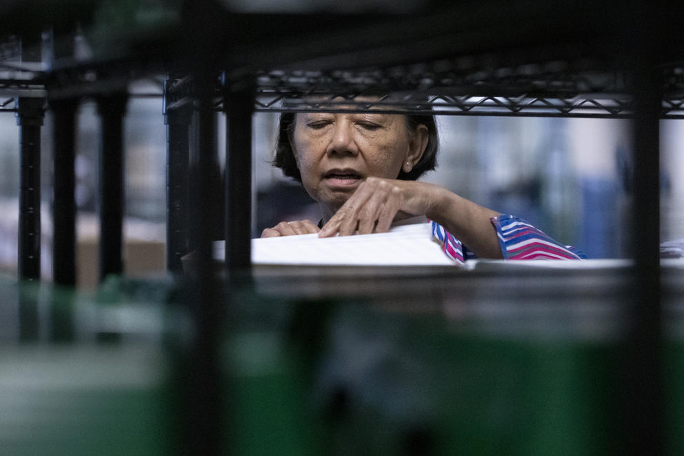 A woman looks through papers on a wire shelf