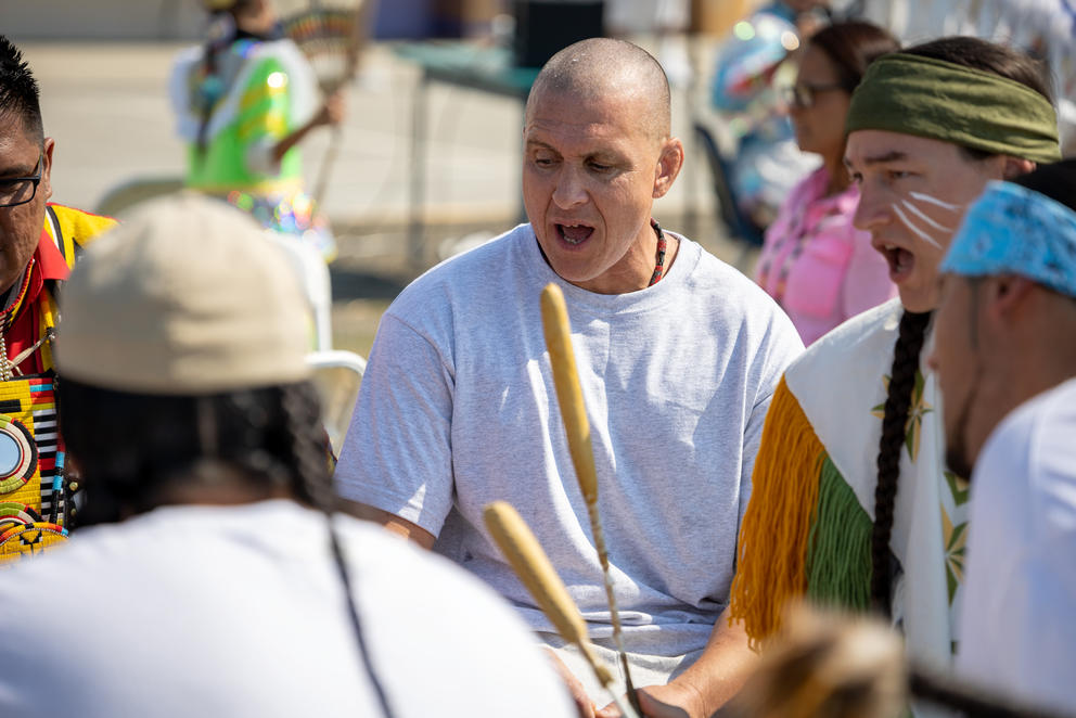 Jarrod Airington sits and sings with other powwow participants