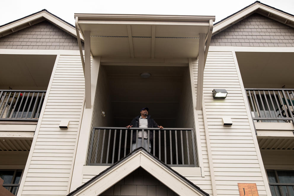 James Kally stands at the balcony of his apartment building.