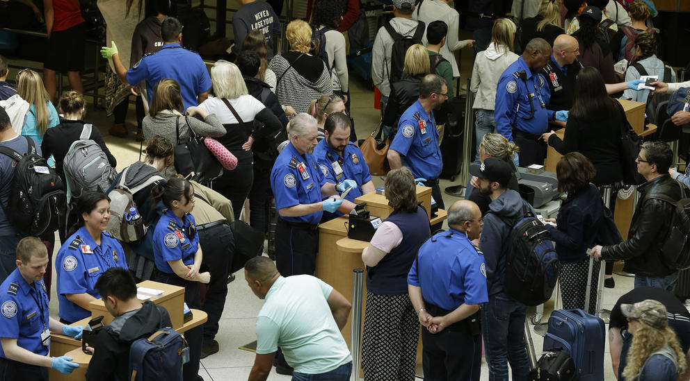 TSA agents check passenger boarding passes at a security checkpoint at Sea-Tac airport.