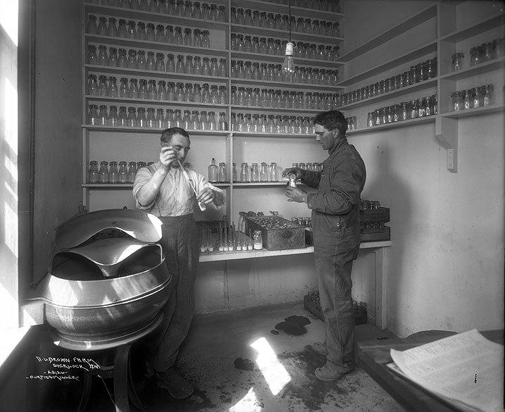 black and white image of men testing milk for safety