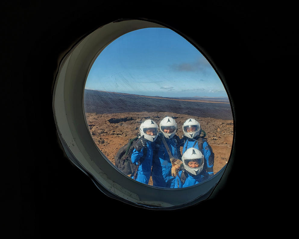 Scientists on land seen through the portal of a ship 
