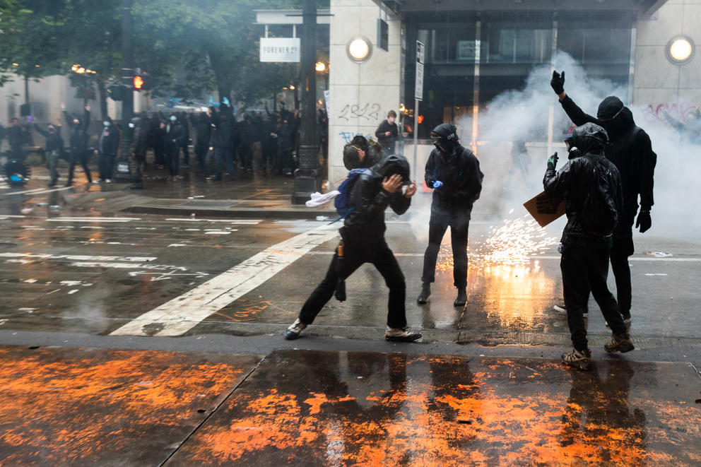 Protesters cover their faces as police deploy blast balls