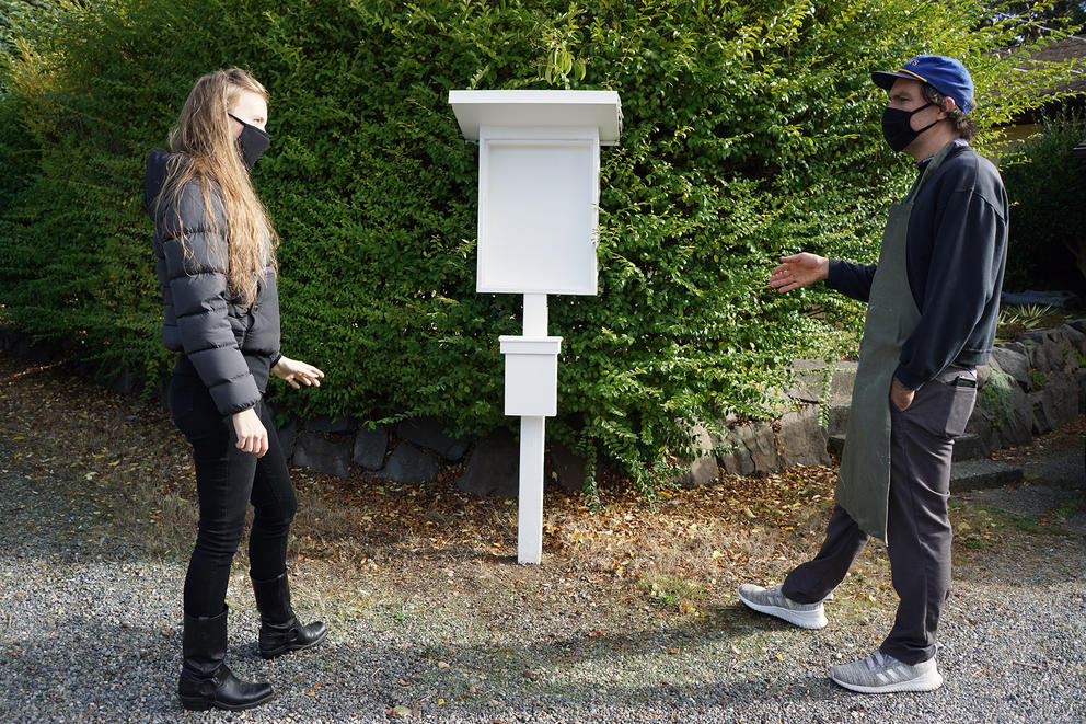 two people look at a white box on a pole