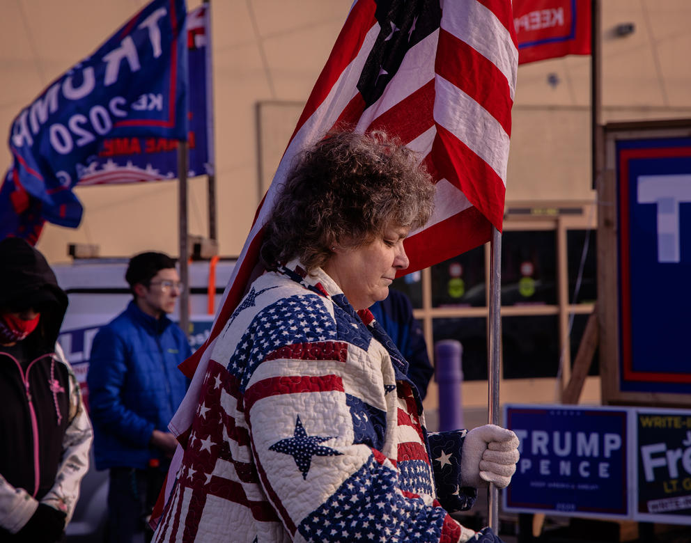 A woman stands outside with an American flag