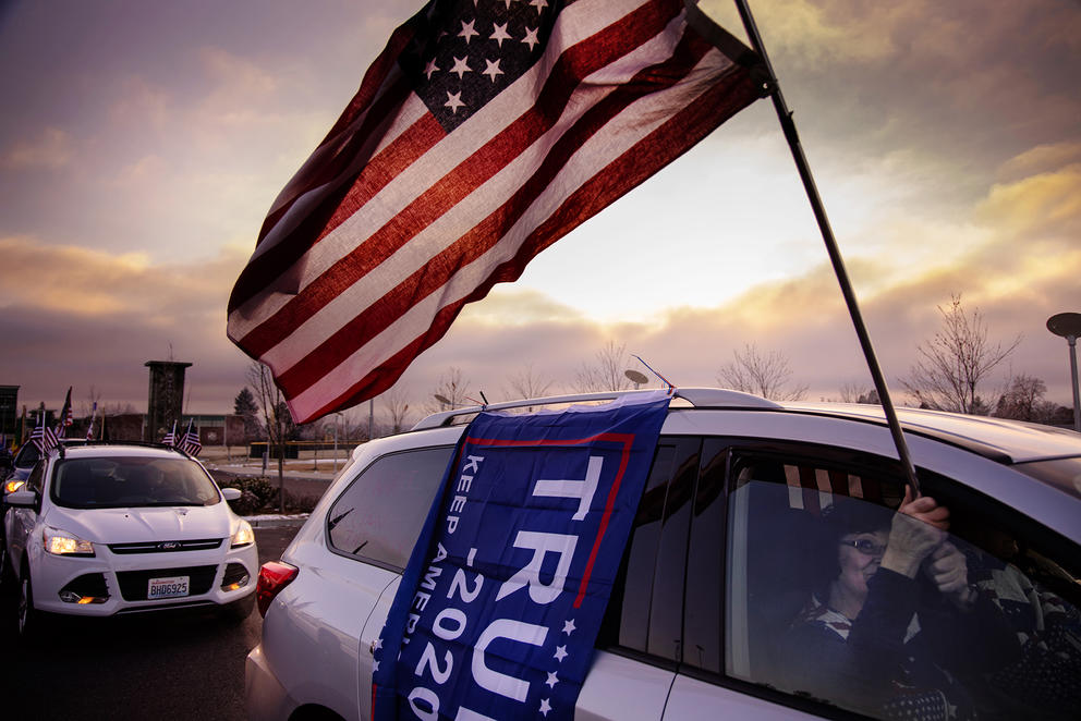 An American and a Trump flag fly outside of a van