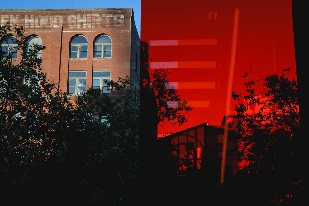 tinted glass stairwell in red (right), brick building (left) 