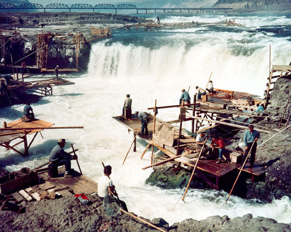 Photograph of people dipnet fishing from platforms built by a waterfall