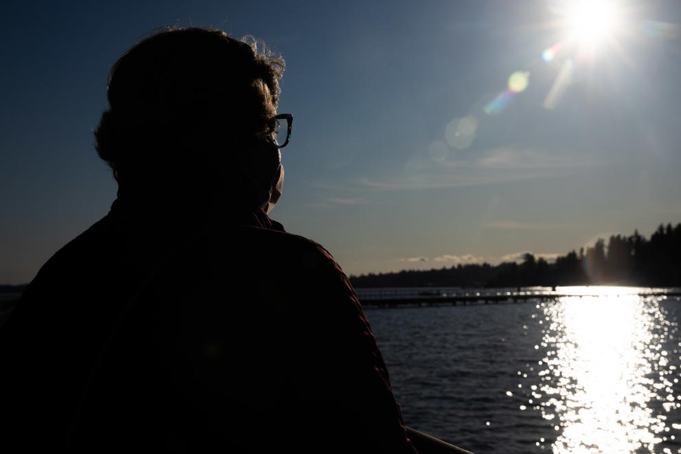 a backlit person looks out at the water