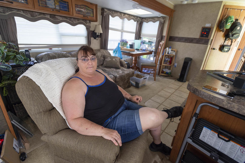 A woman sits in an armchair inside a trailer