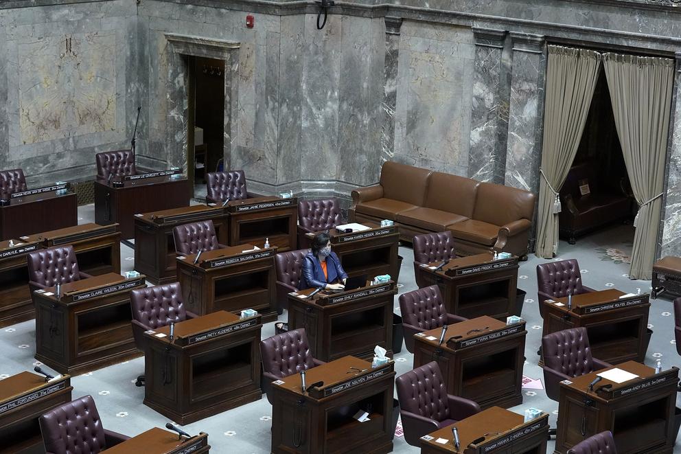 A senator sitting on the Senate floor, while surrounded by empty desks