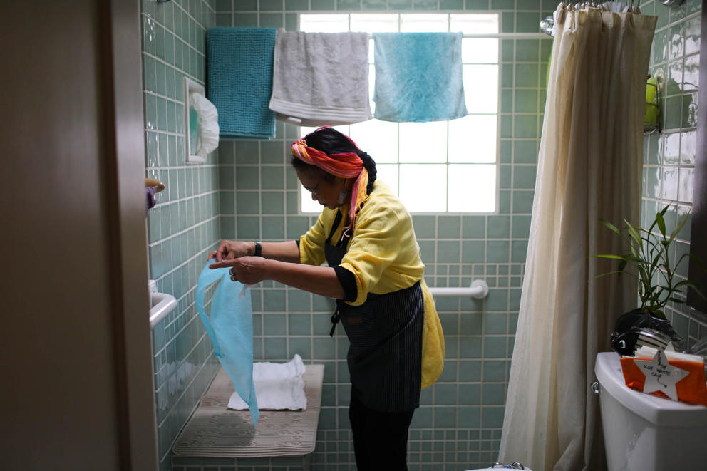 A woman folds small towels in a bathroom