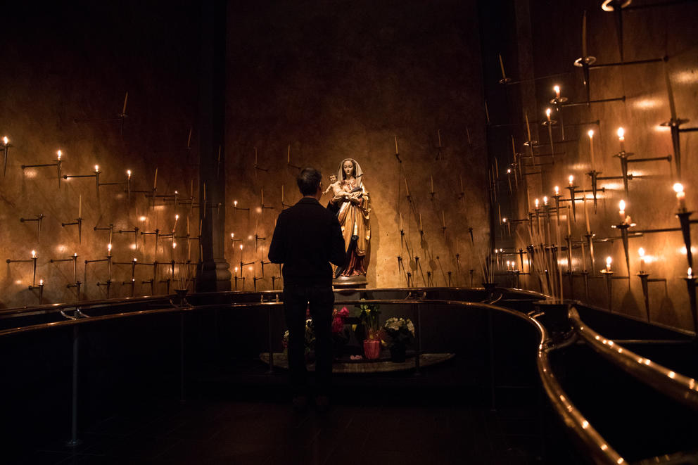 A parishioner stands inside a candlelit altar with Virgin Mary and Jesus during a public veneration at St. James Cathedral in Seattle. 