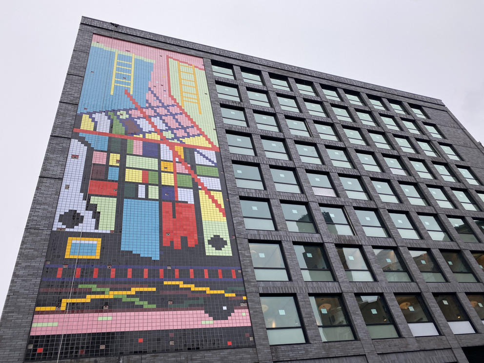 a tall building with a colorful vertical tile mural running up the height