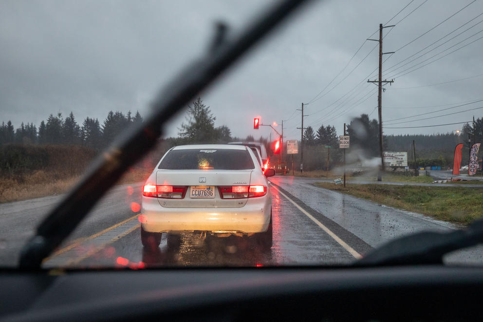 A view through a vehicle windshield shows the rear of a car approaching the Grass Creek Bridge.