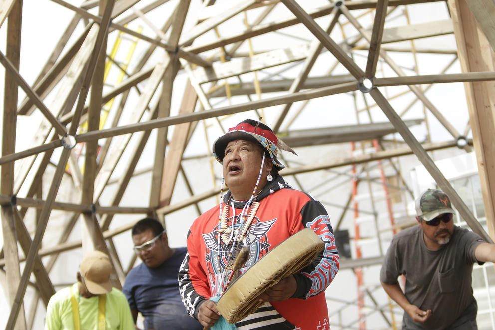 Dan Nanamkin, director of Young Warrior Society, center, leads a prayer for the land inside a geodesic dome under construction 