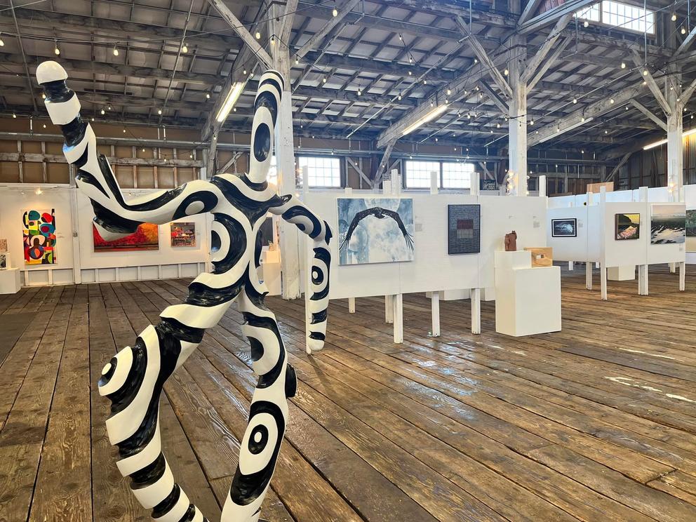 a photo of an art show in a big warehouse with a wooden floor