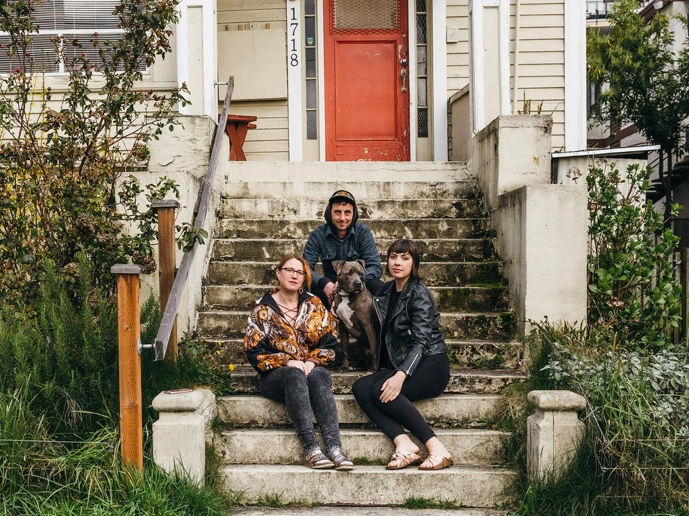Three people sitting on the front steps of their house